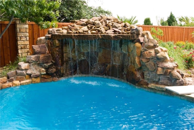Custom stone grotto waterfall feature in a backyard pool