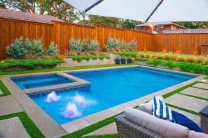 Rectangle pool surrounded by a privacy fence and landscaping