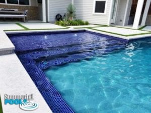 backyard pool with blue glass tanning deck and bubblers