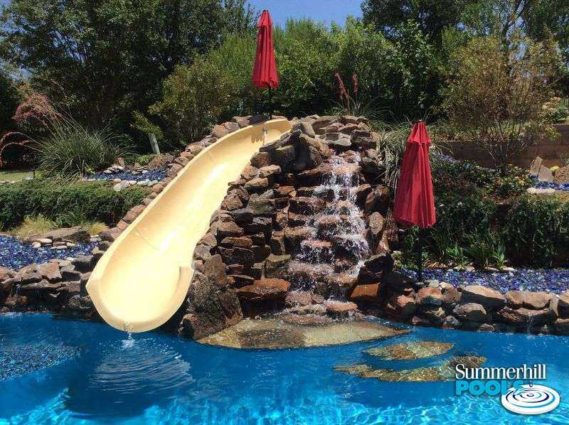 Pool with waterfall steps to a slide.