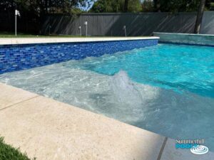 water feature in a pool with blue glass tile